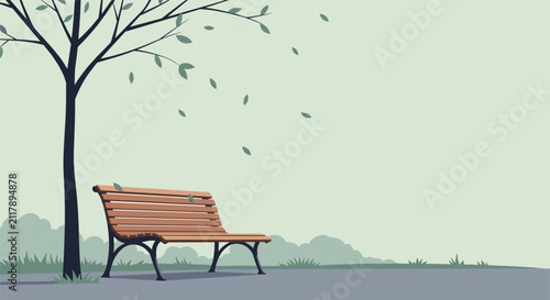 Lonely empty wooden bench in the public park under a leafless tree with blowing leaves during a windy autumn day.