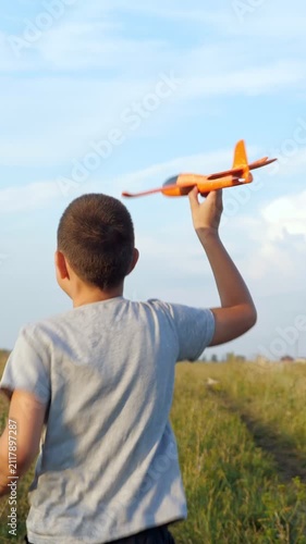 Carefree childhood dreams of a young boy running through a summer meadow with a toy airplane in his hand. Happy kid playing outdoors, imagining being a pilot and traveling the world on a sunny day