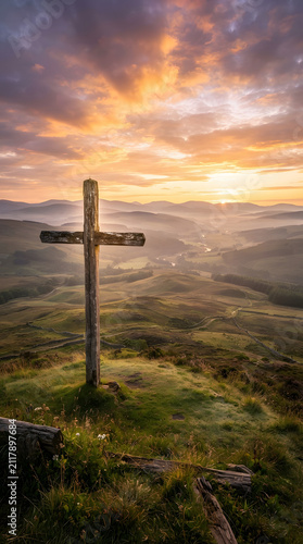 Wooden cross standing in golden sunrise field. Rustic religious symbol illuminated by dawn light on misty hilltop.