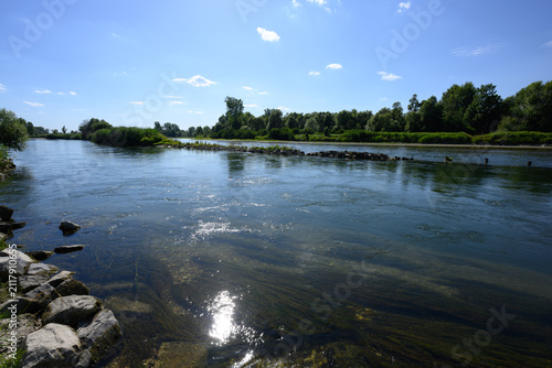 Ein Fluss fließt durch eine grüne Landschaft an einem sonnigen Tag