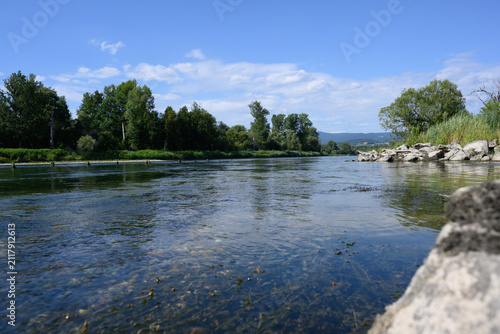 Ein Fluss fließt durch eine grüne Landschaft unter blauem Himmel