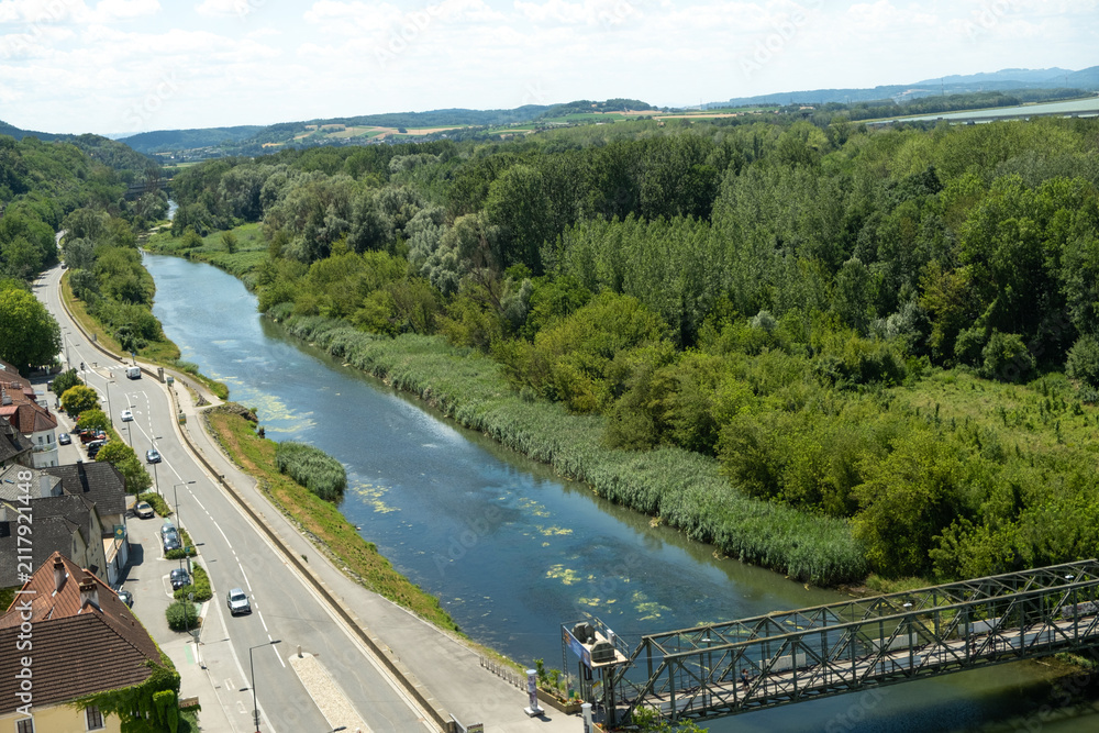 Fototapeta premium Beautiful top view of a European river bend, green lush forest and a road with cars