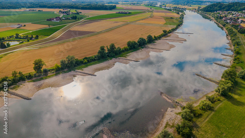 Ein Fluss fließt durch eine Landschaft mit Feldern und Bäumen in der Nähe einer Siedlung