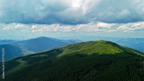 Foto Endless trees carpet a rounded summit under shifting light