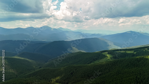 Obraz na plátne Soft light grazes sloping forests while distant peaks rise through haze