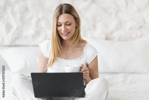 Foto Smiling Young Caucasian Female Working On Laptop While Enjoying Coffee In Cozy Home Environment