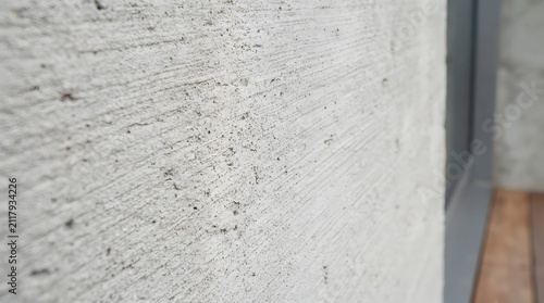 Close up view of a rough concrete wall surface with a blurred wooden floor in the background