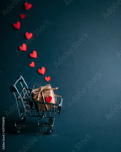 Shopping Cart with Gift Box and Floating Red Hearts on Dark Background for Online Shopping Concept