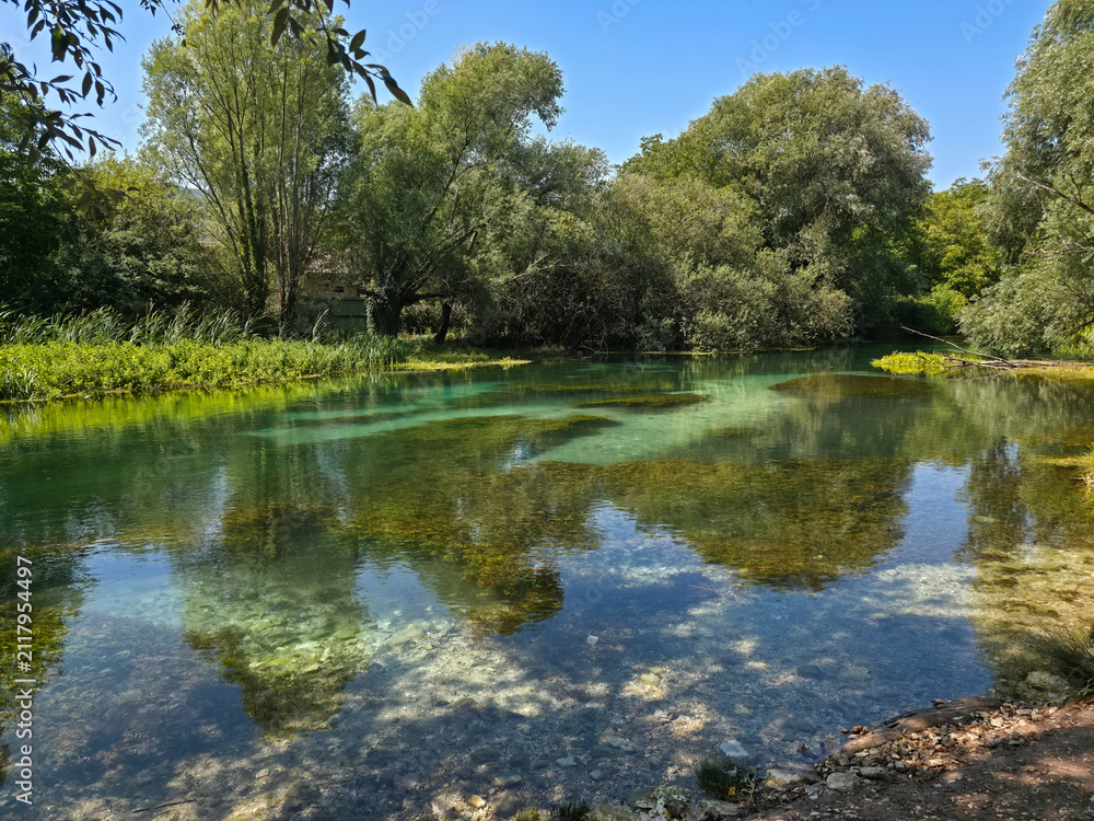 Fototapeta premium Scenic View of Crystal Clear Turquoise Water of Tirino River Surrounded by Green Trees in Capestrano, Abruzzo, Italy