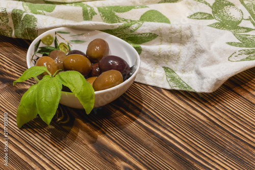 Bild auf Leinwand Mixed olives with basil on rustic wooden table and linen cloth