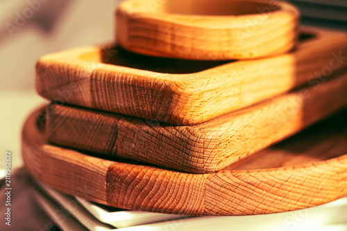 Wooden trays stacked on a table next to ceramic plates in a kitchen setting