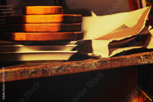 Wooden trays stacked on a table next to ceramic plates in a kitchen setting