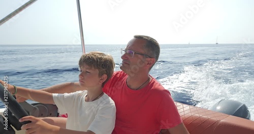 Father teaches son the driving of speed motor boat on the sea, enjoy time together in summer vacation