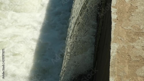 Water flows over the edge of a dam creating a splash in a river	
