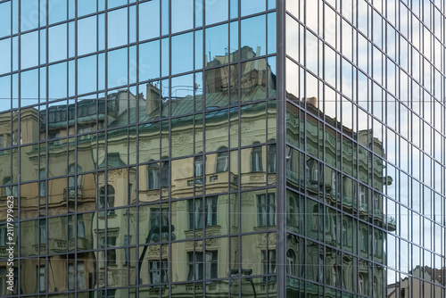 Fotografie Historic architecture reflection in modern glass building facade in Prague
