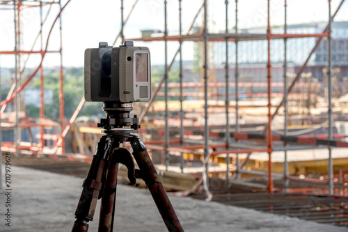Surveying equipment stands on a tripod at a construction site