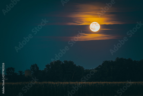 Full moon also know as Buck moon shining moonlight on night sky illuminating clouds