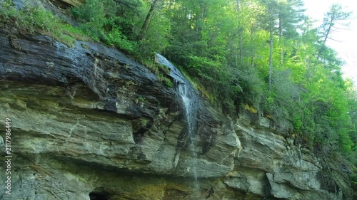 A small waterfall. Splashes of water, stones and grass close-up