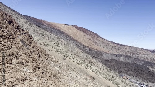 Breathtaking high angle view from moving cable car cabin ascending Teide volcano slopes in Tenerife. Beautiful panorama of desert mountain landscape, basalt layers and tiny tourist parking lot below.
