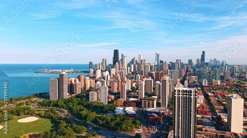 Moving over the green shore of Lake Michigan on sunny day. Approaching the cluster of multiple high-rises in the cityscape of Chicago, Illinois, USA.