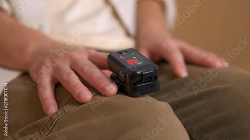 Person measuring oxygen saturation and pulse rate with fingertip oximeter. Close-up of a person's hands while using a portable pulse oximeter to check their blood oxygen saturation level