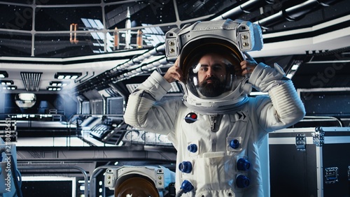 Fotografie A portrait shows a joyful cosmonaut putting on a helmet before mission launch; the upbeat astronaut follows the orbital trajectory while preparing for deep space exploration and human expansion