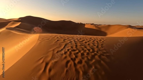 Golden sand dunes stretch across a vast arid desert landscape
