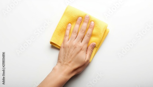 A hand grasping a yellow cloth on a white backdrop.