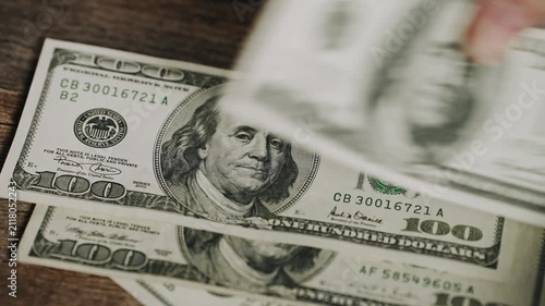 Close-up of hands counting one hundred dollar banknotes on a wooden table. Concept of personal finance, cash handling, savings, budgeting, income, payment, and financial planning.