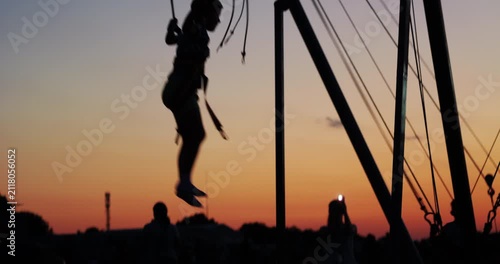 Sunset silhouettes of kids jumping in trampoline