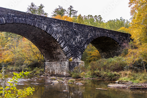 arched stone bridge over a mountain river in the fall