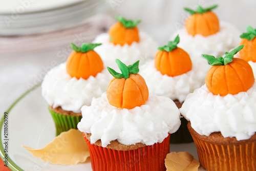 Pumpkin spice cupcakes with white frosting decorated with mini pumpkins made of fondant