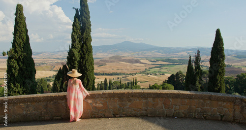 Woman enjoying tuscany val d'orcia landscape with cypress trees