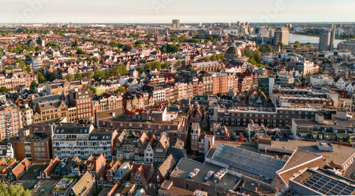 Quadro su tela Warm sunset light bathes a sprawling city as rooftops stretch toward a distant r