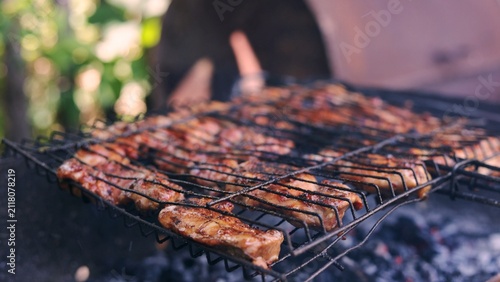 Canvastavla Juicy meat sizzling on a hot grill with charcoal embers glowing below