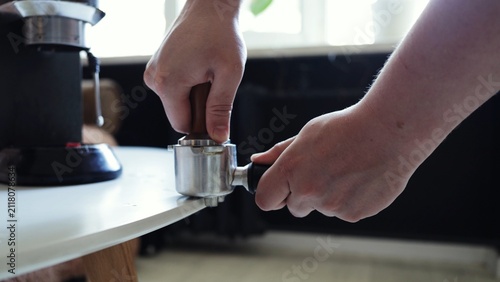 Foto Barista tamping espresso grounds in a portafilter with a tamper