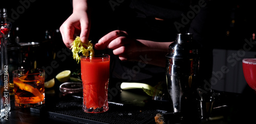 Принти на полотні Bloody mary tomato cocktail preparation in bartender hands at dark bar