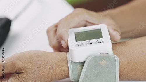 Close-up of a senior adult using a digital wrist blood pressure monitor to measure blood pressure at home. Healthcare monitoring, cardiovascular wellness, hypertension prevention, self care and health