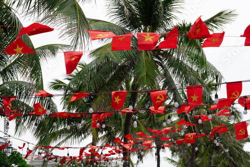 Foto Vietnamese national flags decorating tropical street with palm trees and festive atmosphere