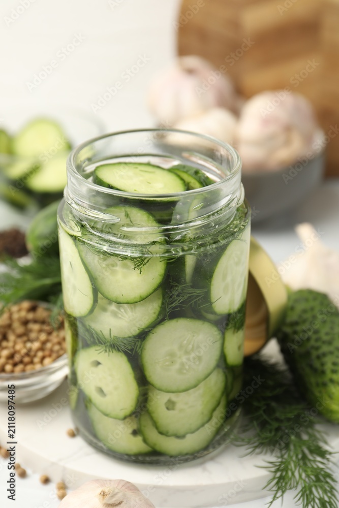 Naklejka premium Making pickles. Fresh cucumbers in glass jar and spices on table, closeup
