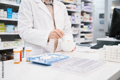 Pharmacist preparing medication in a pharmacy, dispensing pills and capsule