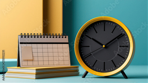 Yellow analog alarm clock with blank calendar on stack of books. Retro desk arrangement representing time management, schedule planning, deadline and organization concept for office work.