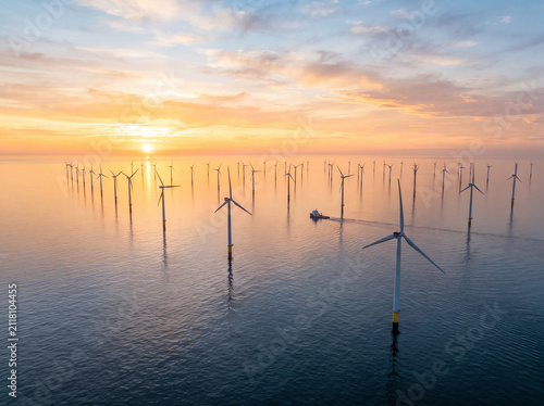 sunset on the lake, Offshore wind farm wind turbines generating clean energy at golden sunset sunrise over ocean