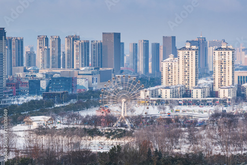 Canvastavla A snowy urban landscape featuring a ferris wheel and high-rise buildings under a pale sky