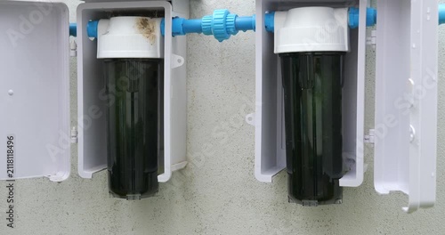 Outdoor dual water filter system installed on white wall