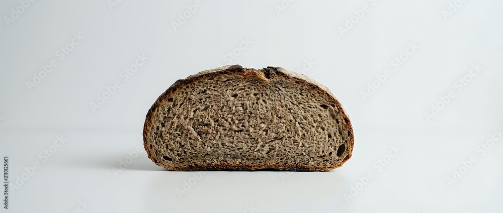 Obraz premium Sliced whole wheat bread loaf half showing dense crumb structure and texture, suitable for food photography, bakery marketing, and culinary publications.