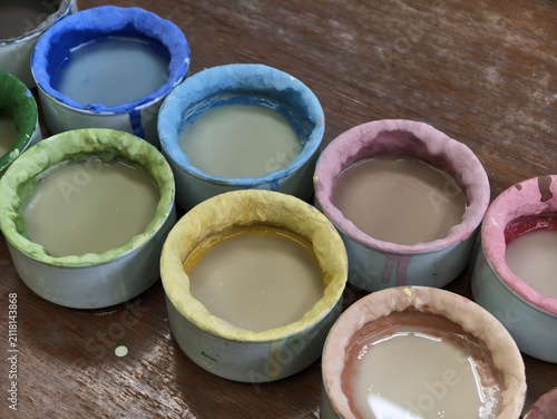 Obraz na płótnie Colorful paint cups rest on a wooden surface