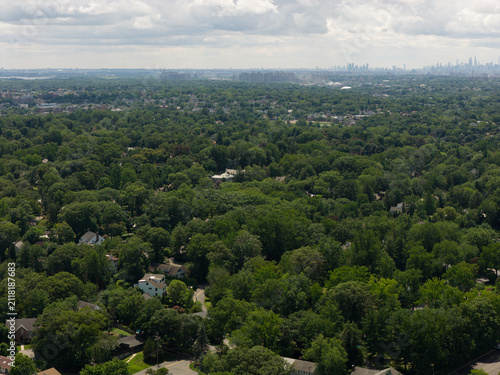 Cuadro en lienzo Aerial drone view of distant city skyline beyond a wooded suburban landscape in