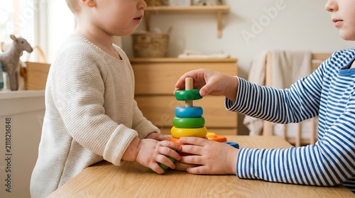 Two Young Siblings Engaging in Creative Developmental Play with Colorful Wooden Stacking Rings Together at a Table in a Cozy Nursery