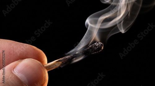 Obraz na plátně Macro close up of fingers holding an extinguished burnt matchstick with smoke sw